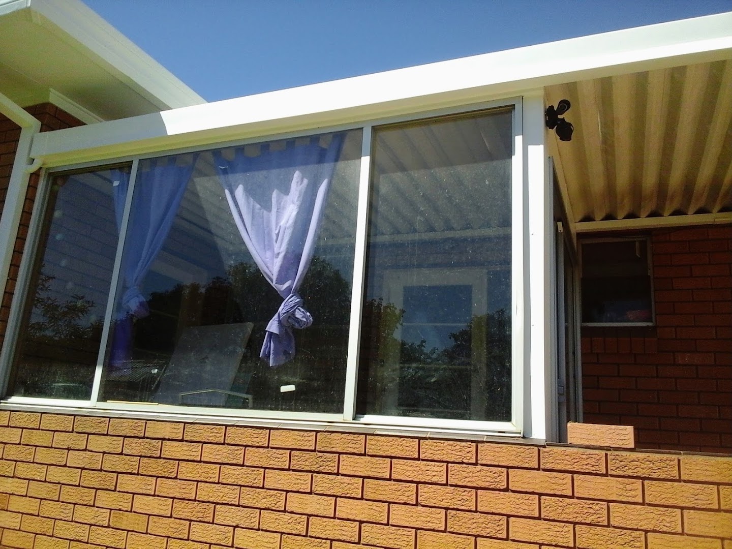 A brick home with a wide window and a curtain drawn back