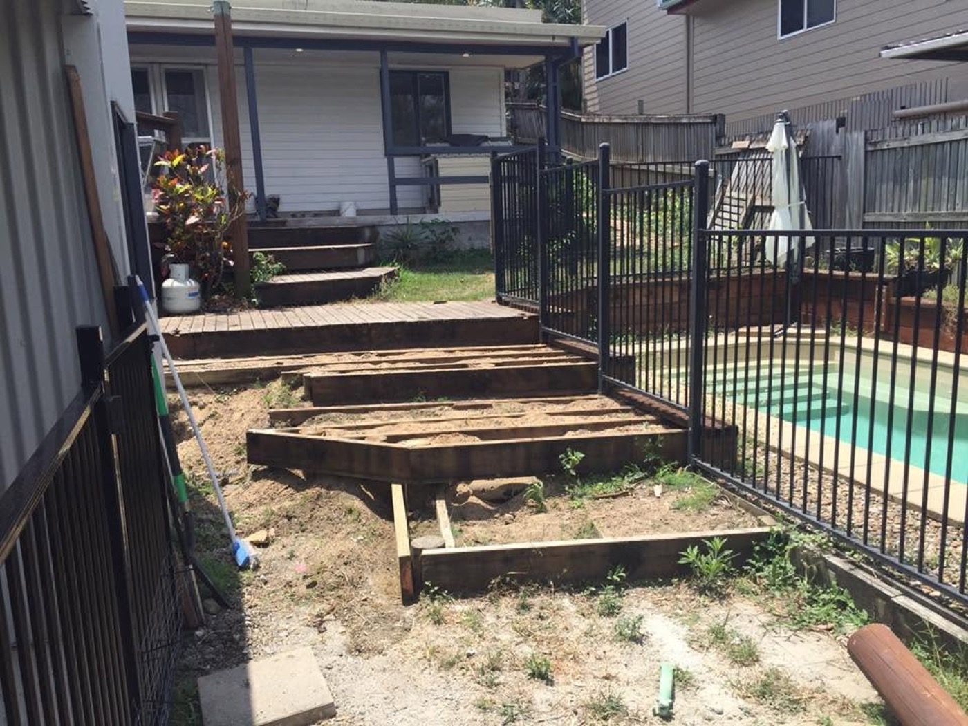 Timber deck framing going in beside a pool, with steps stacked ready
