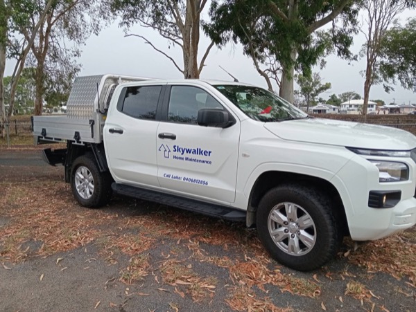 The signwritten Skywalker Home Maintenance ute parked under gum trees