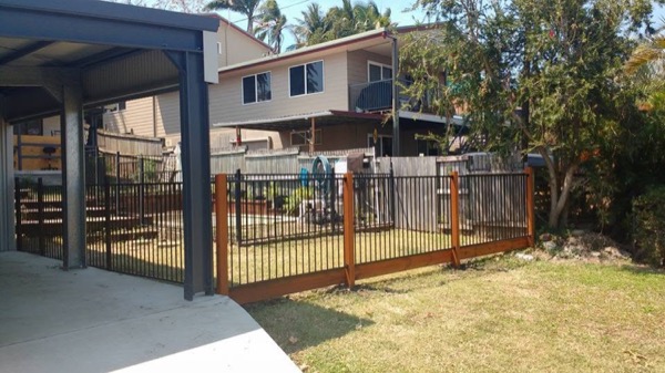 An aluminium pool fence and timber posts beside a carport