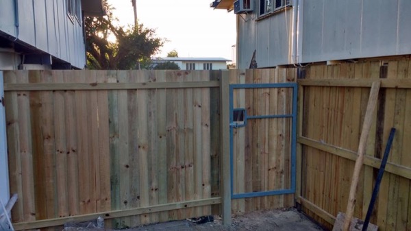 A timber paling fence and gate frame going up between two houses