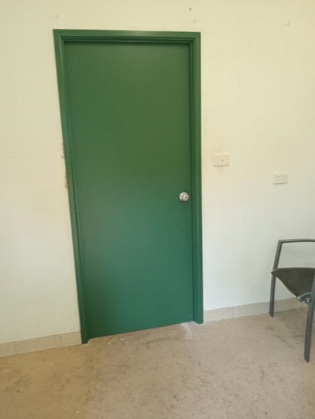 A green painted internal door hung in a pale room
