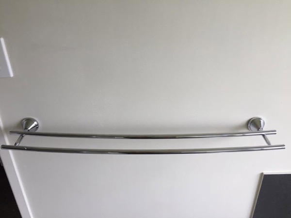 A long chrome towel rail mounted above a benchtop