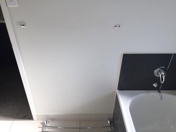A bathroom with a bath and wall mounted tapware