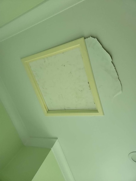 A ceiling access hatch with the surrounding sheet broken away