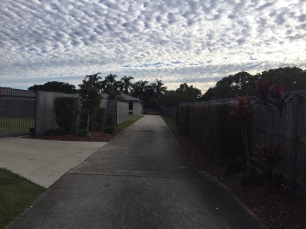 A concrete path running between two fences under a mackerel sky